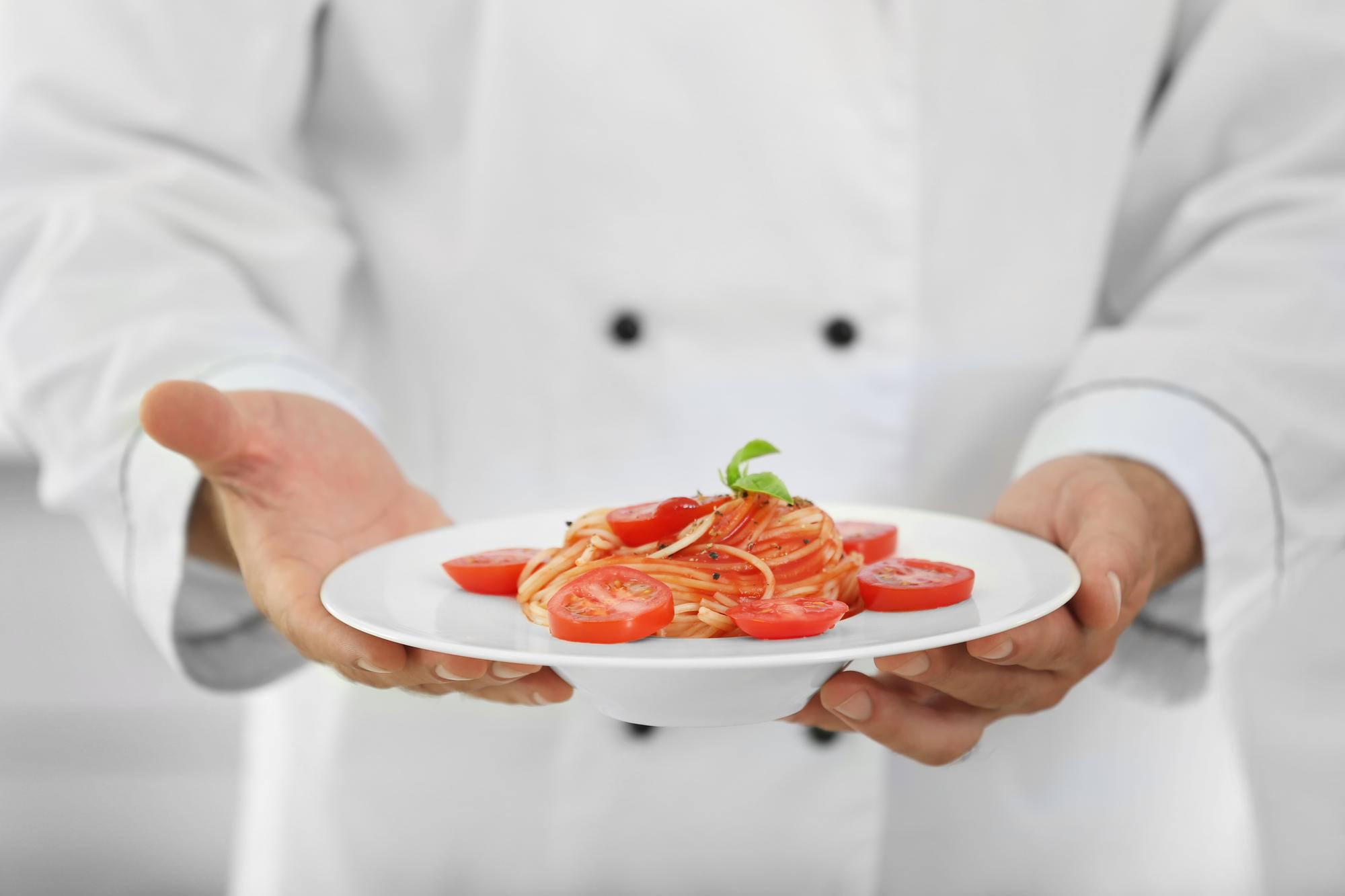 Close up of chef hands plating under warm light